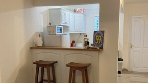 Eine Küche mit weißen Schränken, einer Holzauskładung, zwei Hocker und einem Schild mit 59% Rabatt.