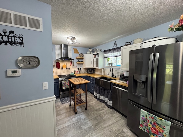 Una cocina moderna con un refrigerador de acero inoxidable, una mesa de madera y diversos electrodomésticos.