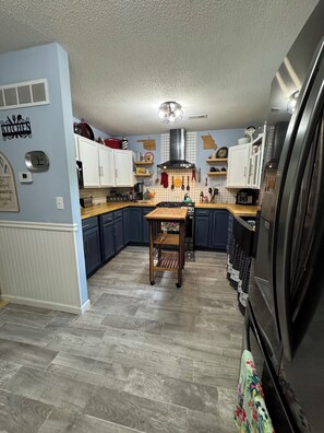 A kitchen with wooden cabinets, a central island, and a refrigerator.