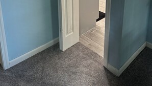 Un pasillo con una puerta que da a un baño, un mapa enmarcado en la pared y un calendario.