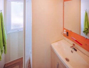 A bathroom with a white sink, a mirror, and a shower door. - Premium Family Escape in Umag (Brtonigla)