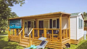 A wooden cabin with a deck, a lounge chair, and a small shed. - Premium Family Escape in Umag (Brtonigla)
