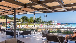 An outdoor seating area with a view of a pool and beach. - Premium Family Escape in Umag (Brtonigla)
