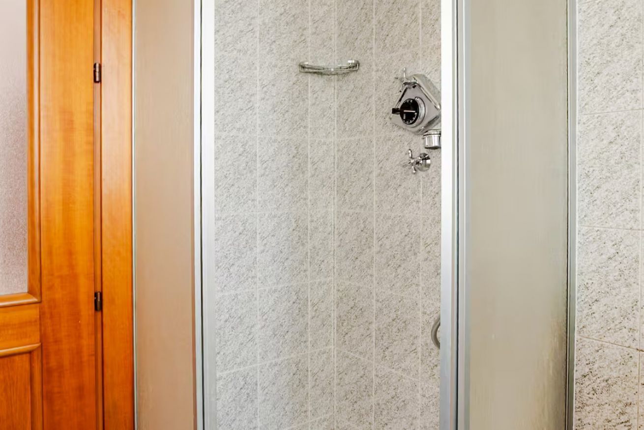 Eine Holztür und eine Duschkabine mit einer gefliesten Wand.