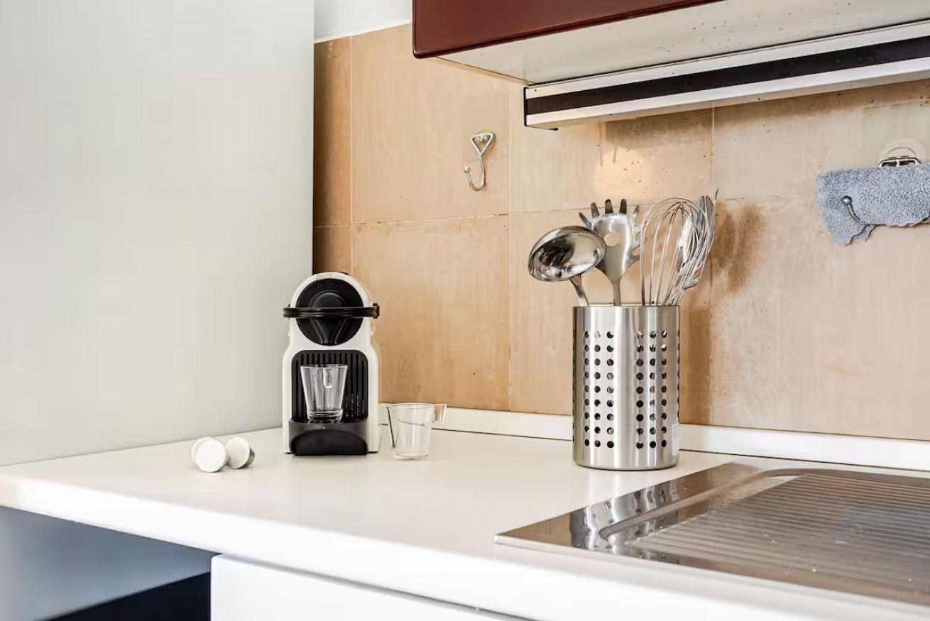 Eine Küchenarbeitsplatte mit Kaffeemaschine, einem Glas und einer Küchenutensilienhalterung.