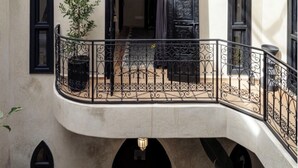 A courtyard with a balcony, arched windows, and a door with intricate metalwork. - Riad 1810 - Private Luxury Riad • Pool • Rooftop Views (Marrakesh)