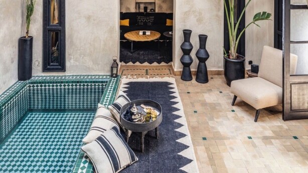 An interior with a high arched ceiling, a seating area with cushions, a round table, and potted plants. - Riad 1810 - Private Luxury Riad • Pool • Rooftop Views (Marrakesh)