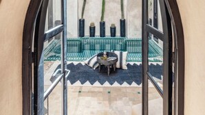 An arched doorway leading to a pool area with a tiled floor and a small table with cushions. - Riad 1810 - Private Luxury Riad • Pool • Rooftop Views (Marrakesh)