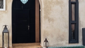 An arched doorway, a small round table with a teapot and glasses, and a tiled pool area. - Riad 1810 - Private Luxury Riad • Pool • Rooftop Views (Marrakesh)