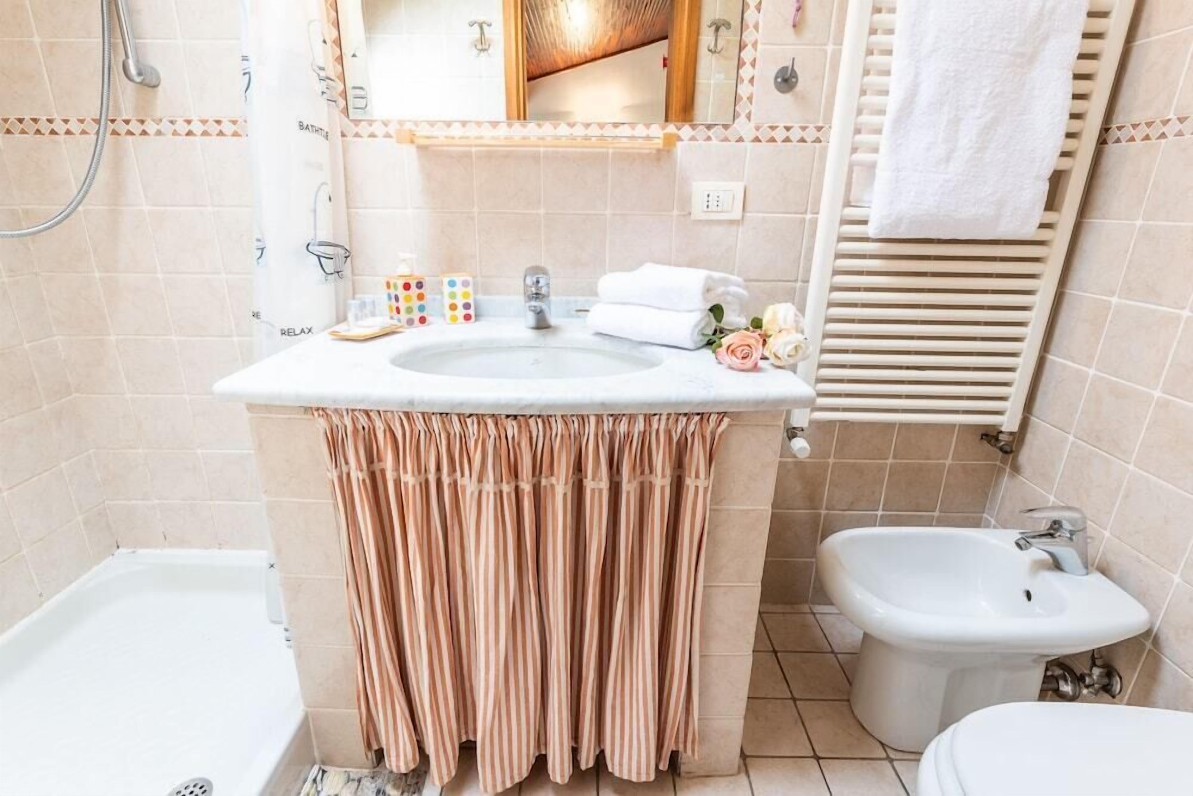 Ein Badezimmer mit Waschbecken, Spiegel, Handtuchhalter und Duschwc.