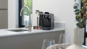 A modern kitchen with a built-in coffee maker, stainless steel sink, and a window with blinds. - Luxury 4 Guests Villa With Sunny Garden (Workum)