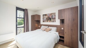A modern bedroom with a large bed, wooden wardrobe, and a window with curtains. - Luxury 4 Guests Villa With Sunny Garden (Workum)