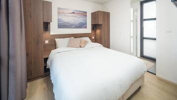 Un dormitorio con una cama grande, cabecera de madera, un cuadro en la pared y una ventana con persianas.