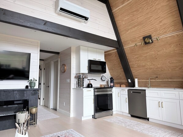 A modern kitchen with white cabinets, a built-in oven, a microwave, and a dishwasher.