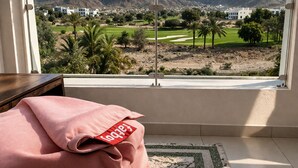 Ett rum med utsikt över berg, en golfbana och stadens silhuett.
