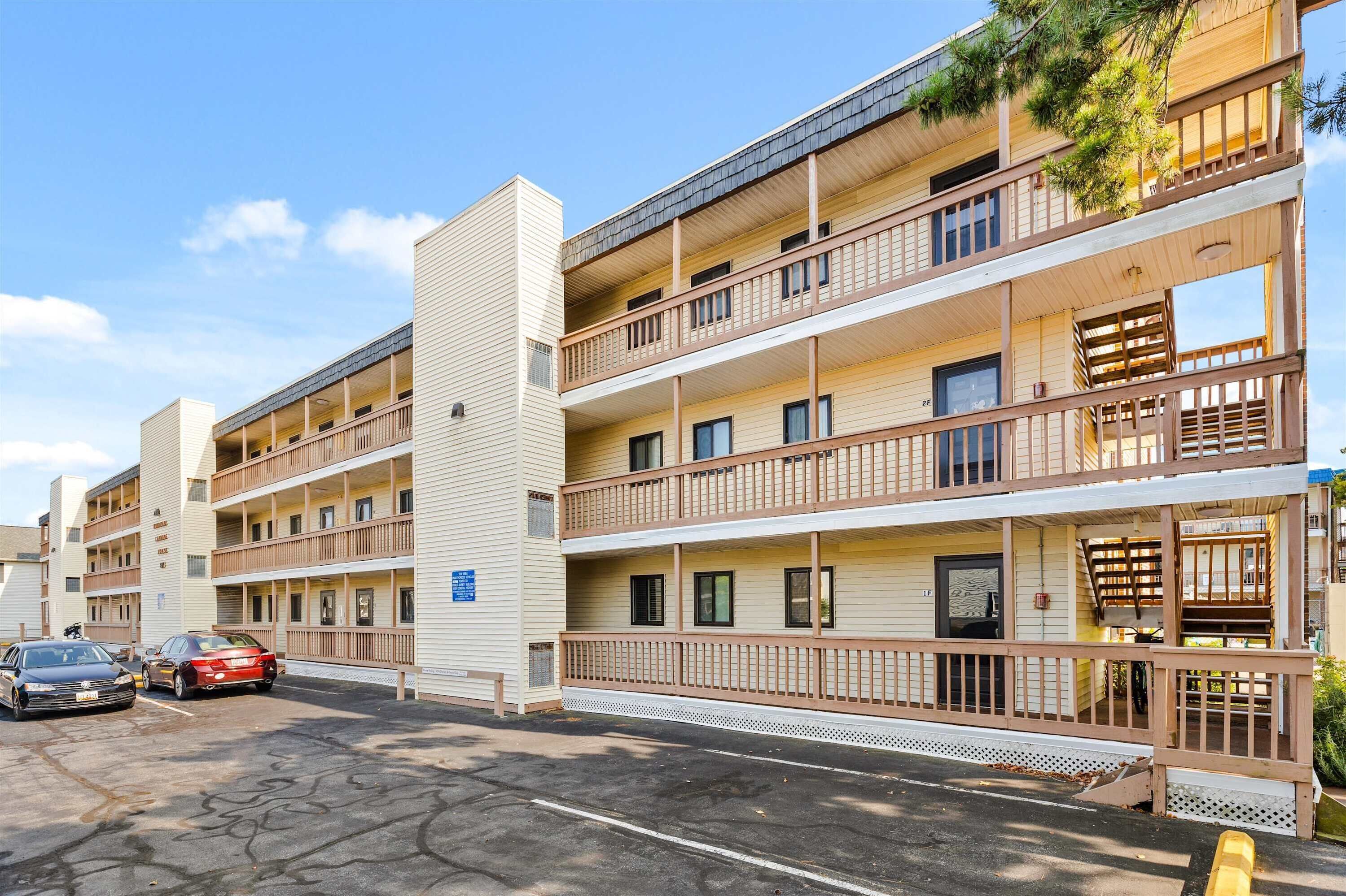 Un hotel de varios pisos con balcones, estacionamiento y cielo despejado.
