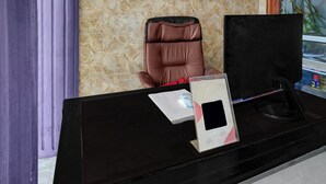 A reception desk with a computer monitor, a telephone, and a chair.