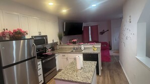 Una cocina moderna con electrodomésticos de acero inoxidable, una isla de encimera de granito y un televisor de pantalla plana montado sobre la isla.
