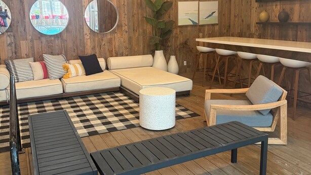 Una sala de estar moderna con un sofá modular, una mesa de centro, una zona de comedor con barra y un espejo grande.