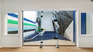 Una habitación con un ventanal grande, suelo de madera y una pared de escalada.