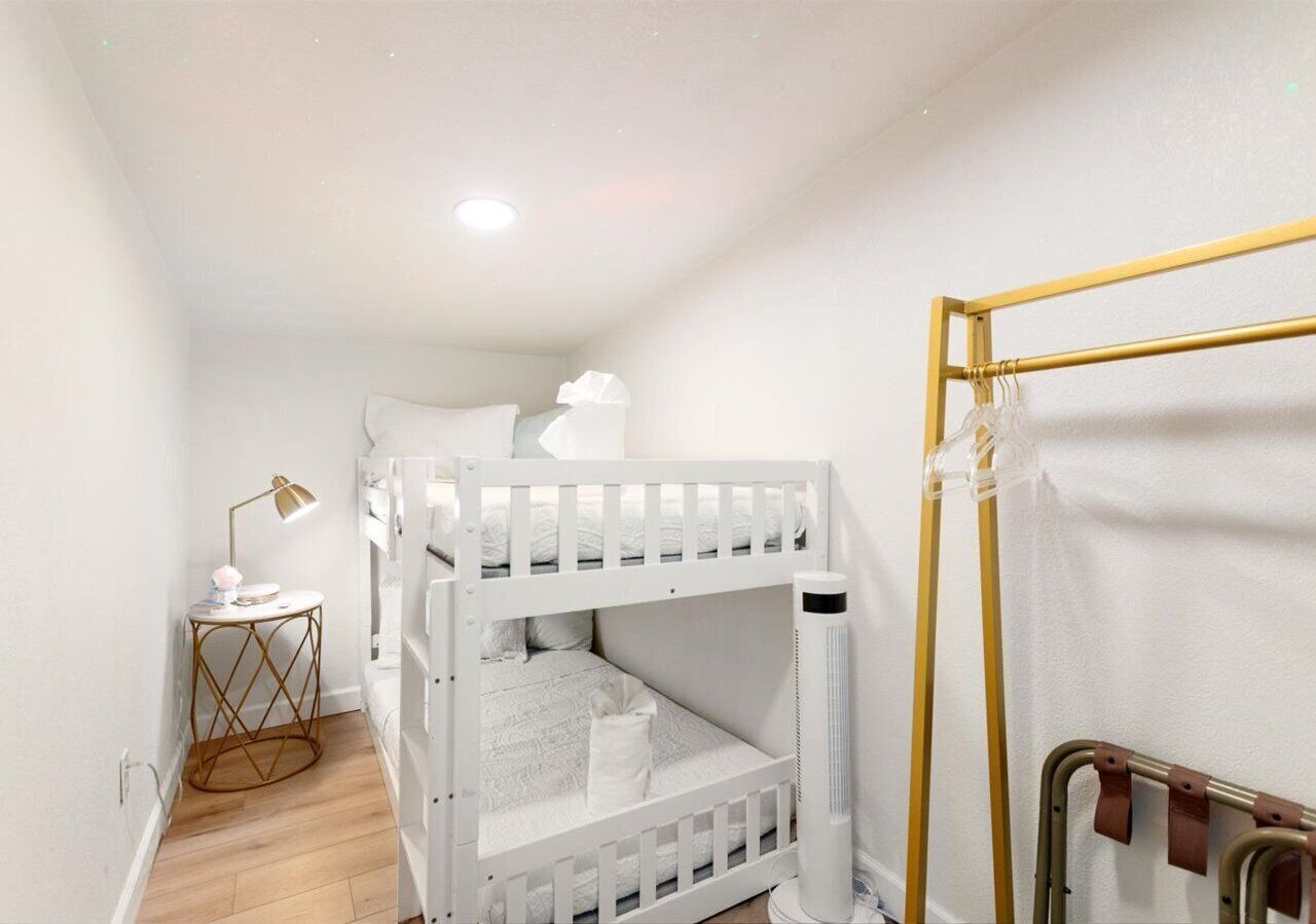 Dormitorio con literas, mesita de noche, lámpara y radiador.