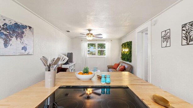 A modern kitchen with a central island, a dining area with a sofa, and a living room with a TV.