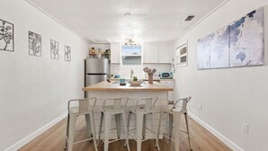 A modern kitchen with a central island, bar stools, a refrigerator, and a microwave.