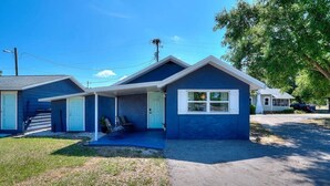 A two-story building with a blue exterior, a front porch, and a visible garage door.