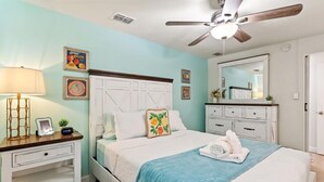 A bedroom with a bed, a nightstand, a dresser, a ceiling fan, and a mirror.