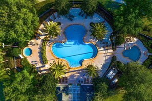 An aerial view of a resort with a central swimming pool, multiple smaller pools, and surrounding lounge areas. - Stylish Home with Pool Hot Tub and Parking (Kissimmee)