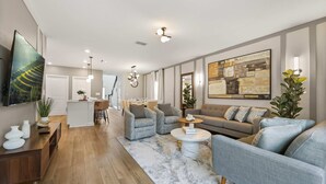 Una sala de estar moderna con un sofá, sillones, una mesa de centro y un televisor.