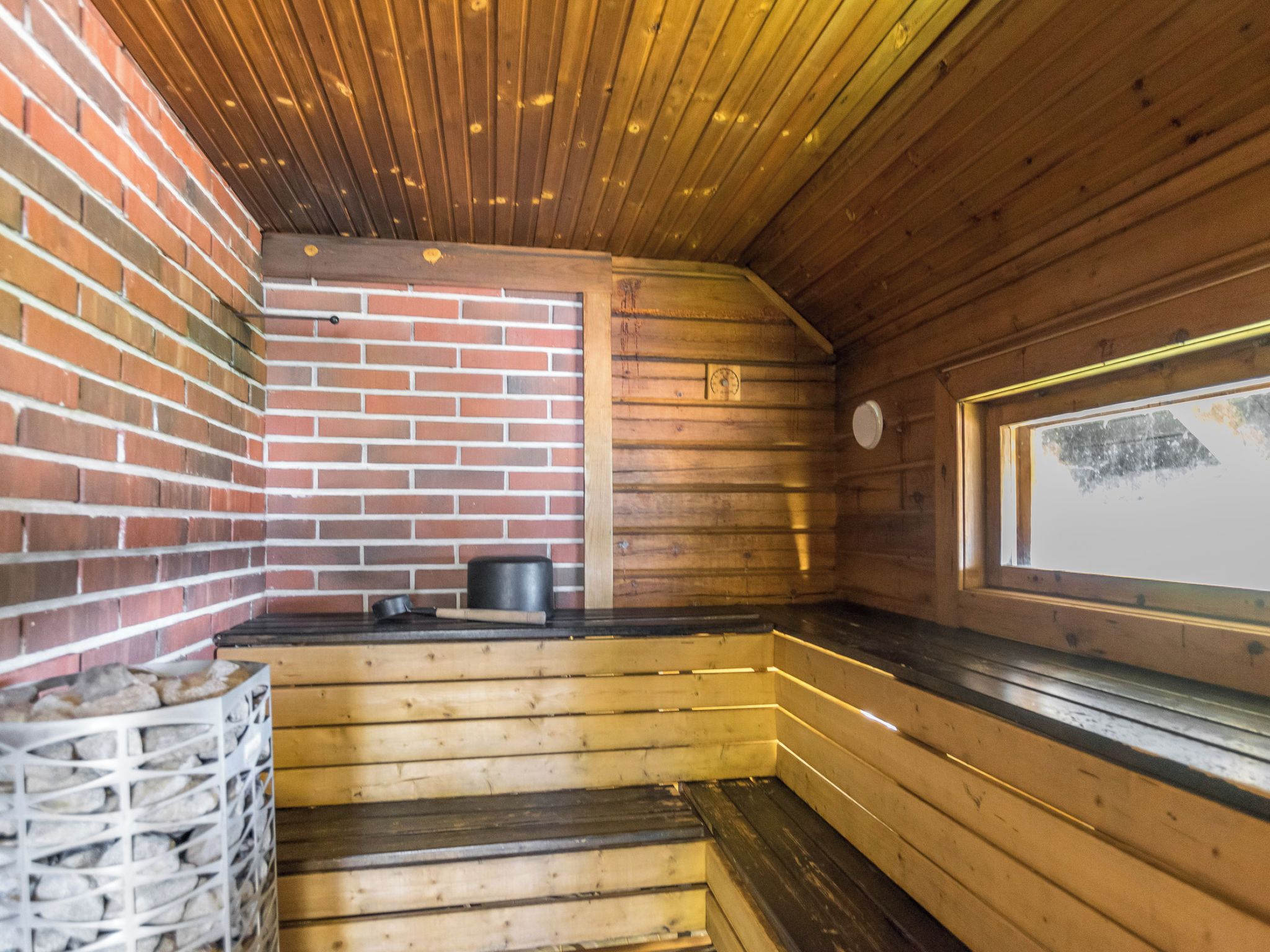 Een sauna met houten banken, een bakstenen muur en een raam.