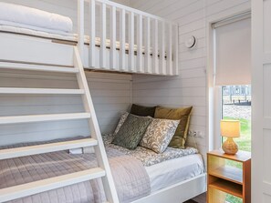 A bunk bed with a ladder, a bedside table with a lamp, and a window with a view of an outdoor area. - Villa orion 57 by Interhome (Kemiönsaari)