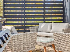 A patio with wicker furniture, a grill, and a wooden fence. - Villa orion 57 by Interhome (Kemiönsaari)