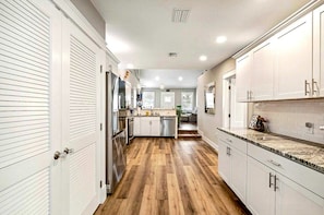 Una cocina moderna con armarios blancos, piso de madera e isla central.