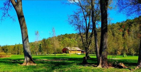 A rural landscape with a barn, trees, and a clear sky.