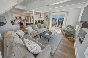 A spacious living area with a sofa set, a coffee table, and a fireplace. - OCEANFRONT 3-Bedroom in Duck: Beach + Pool + Walk to Shops (Duck)