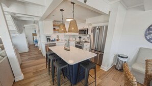 Une cuisine moderne dotée d’un îlot central, de tabourets de bar et d’un réfrigérateur en acier inoxydable.