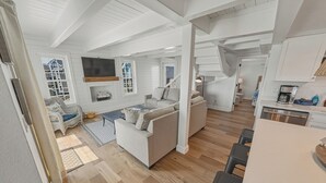 Un vaste espace de vie comprenant un canapé, un téléviseur et un escalier menant à un autre niveau.