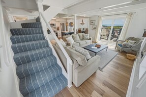 A staircase with a patterned carpet, a sofa set with cushions, a coffee table, and a view of the outdoors. - OCEANFRONT 3-Bedroom in Duck: Beach + Pool + Walk to Shops (Duck)