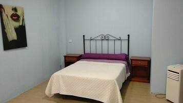 Un dormitorio con una cama, una mesita de noche, un calentador y un cuadro colgado en la pared.