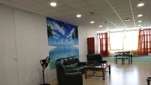 Una habitación amplia con un gran mural en la pared, un sofá de cuero negro, una mesa de centro de madera y un comedor con mesa y sillas.