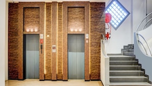 Um elevador moderno com painéis de madeira e um mangueira de incêndio vermelha na parede.