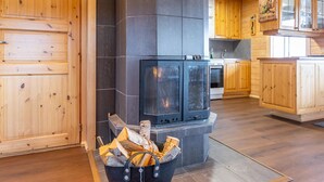 A wooden interior with a fireplace, wooden cabinets, and a kitchen area.