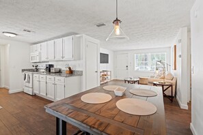 A spacious kitchen with white cabinets, a large wooden island, and a hanging light fixture. - 3BR Pool Putting Green | Good Morning Rentals (Jacksonville Beach)