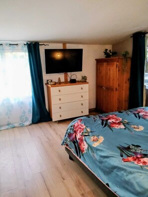 Ein Schlafzimmer mit Bett, Kommode, Fernseher und Kleiderschrank.