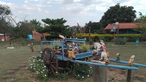 A garden with a blue bench, wooden stools, and various sculptures. - Chalet São Jorge where nature predominates (São Pedro)