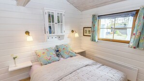 Un dormitorio con cama, ventana con cortinas, armario y luces en la pared.