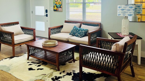 A living room with a wooden coffee table, two sofas, a cowhide rug, and a window with blinds.