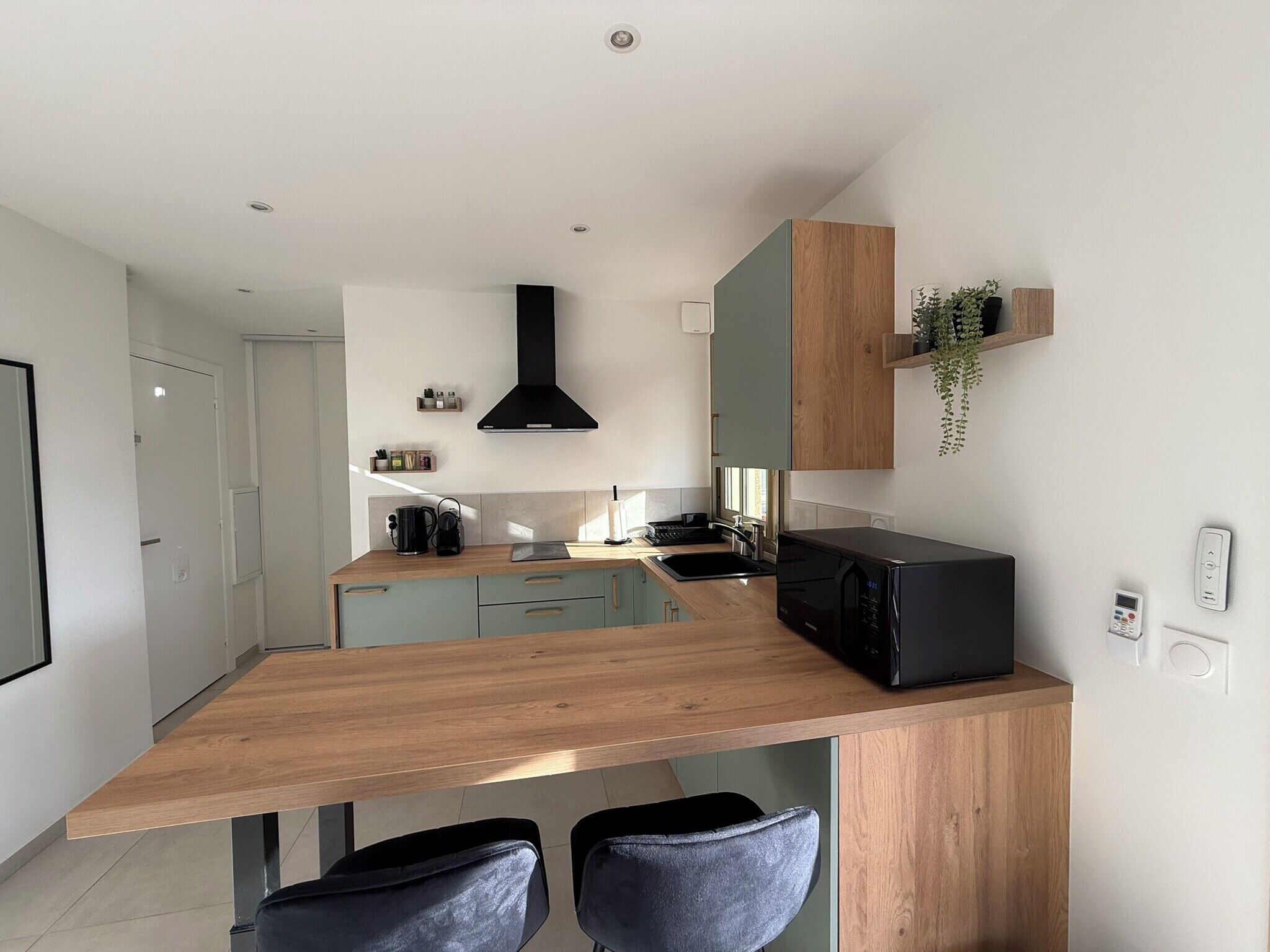 Una cocina moderna con encimera de madera, electrodomésticos negros y placa de cocina integrada.